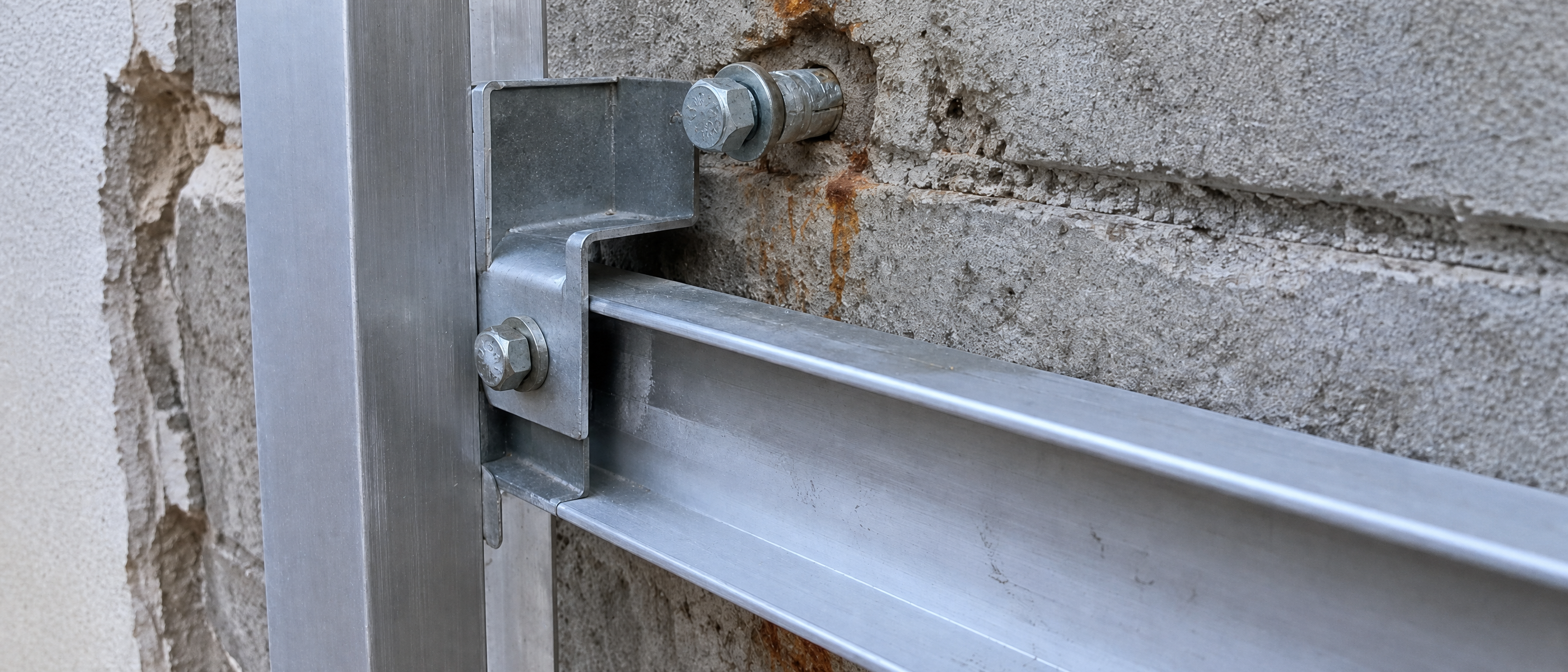 Aluminum Z-rail subframe anchored to concrete block wall — ACP cladding installation detail